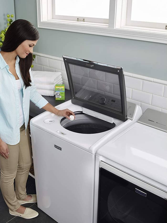 a model dropping one of the tablets into the washing machine 