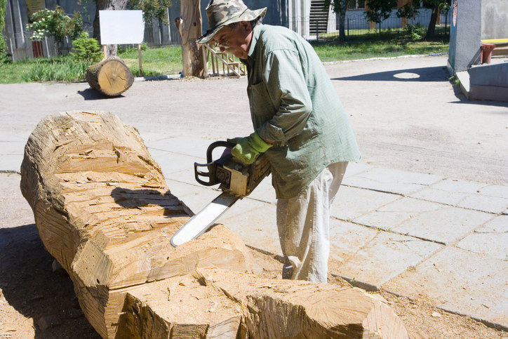 Stock photo of a man cutting wood with a chainsaw.