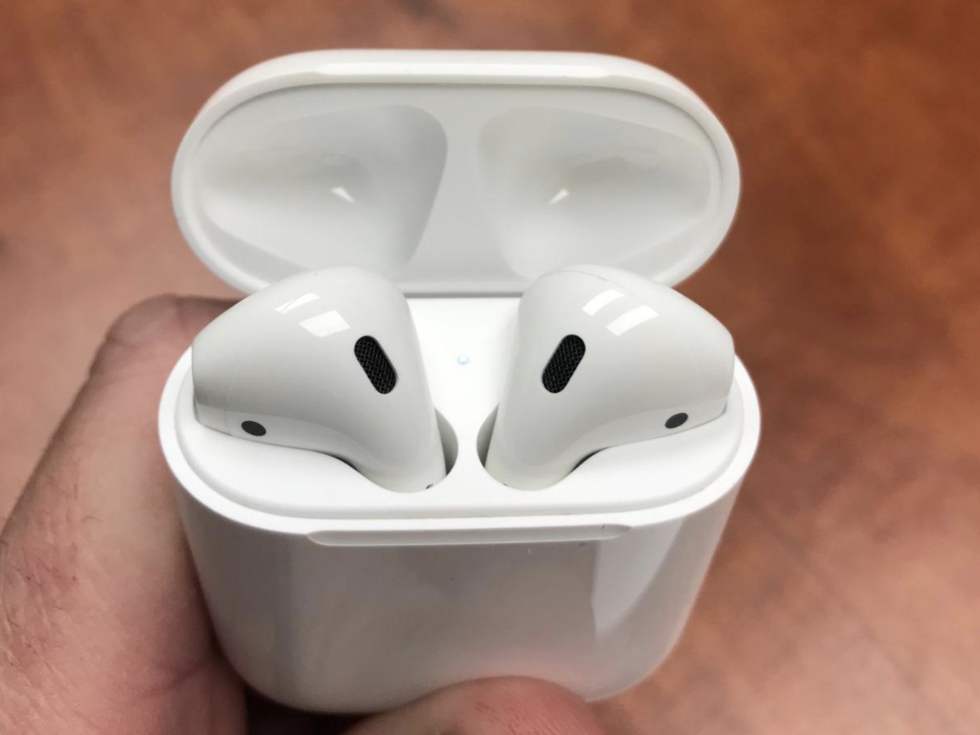 reviewer holding white airpods in white charging case