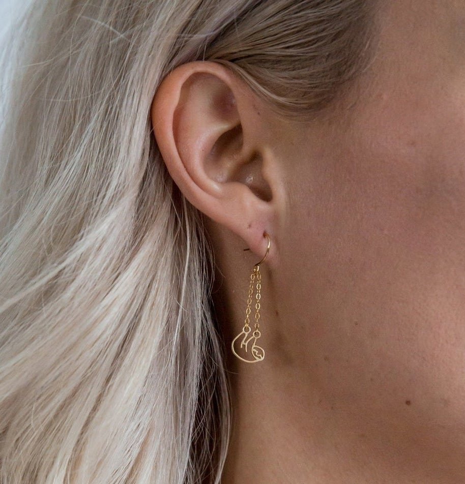 A person wearing the sloth earrings