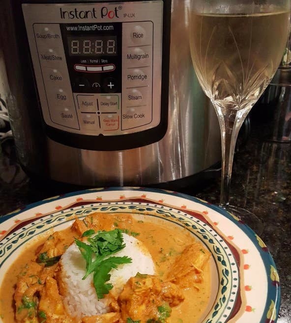 A reviewer photo of the Instant Pot next to a plate of butter chicken that they made using the Instant Pot