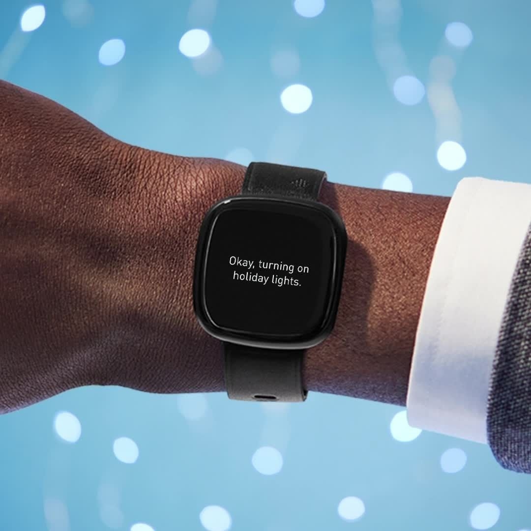 A person wearing the smart watch on their wrist with the message, okay, turning on holiday lights scrolling on the screen