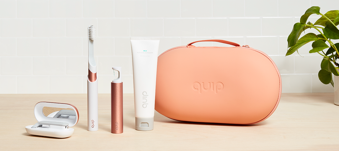 A quip toiletry case, floss holder, tube of toothpaste, and toothbrush 