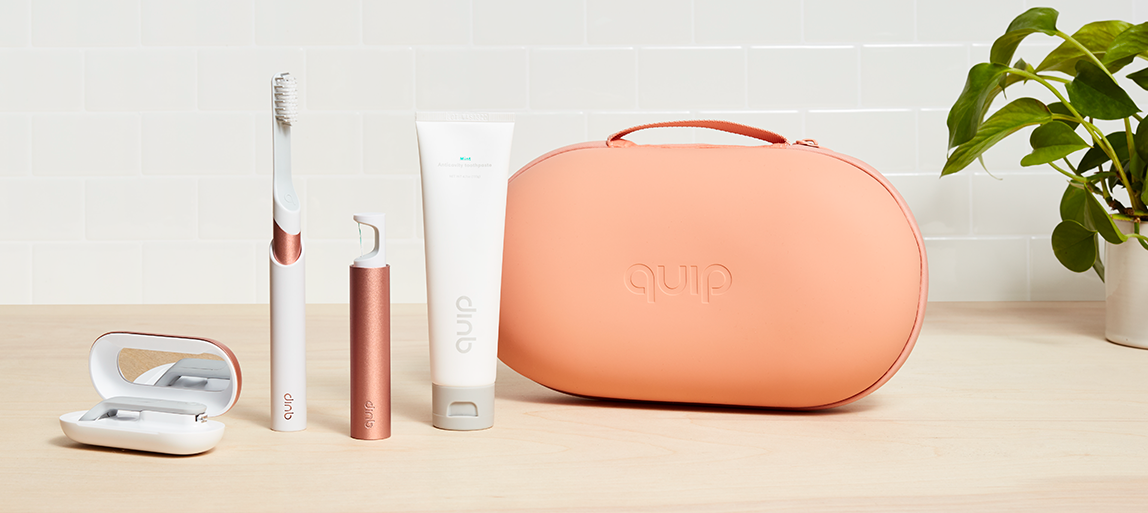 A quip toiletry case, floss holder, tube of toothpaste, and toothbrush 