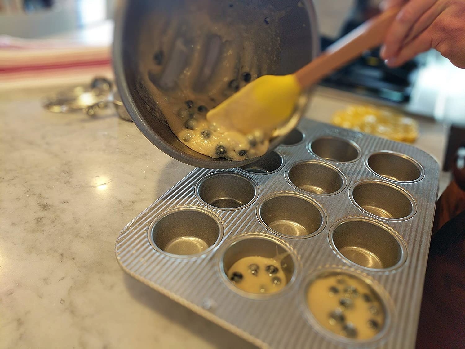 batter being poured into the muffin tin