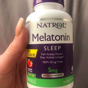 Reviewer holding up bottle of sleep tablets 