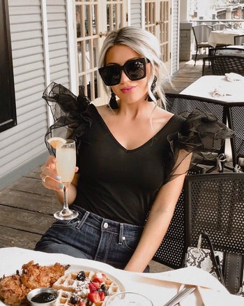 A reviewer in the black sleeveless bodysuit with sheer tulle puff shoulders