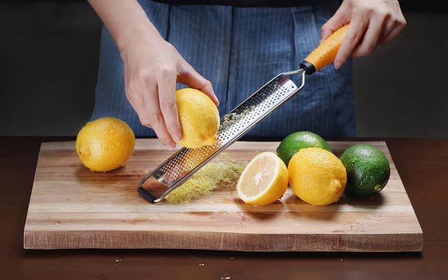 a model zesting a lemon over a cutting board
