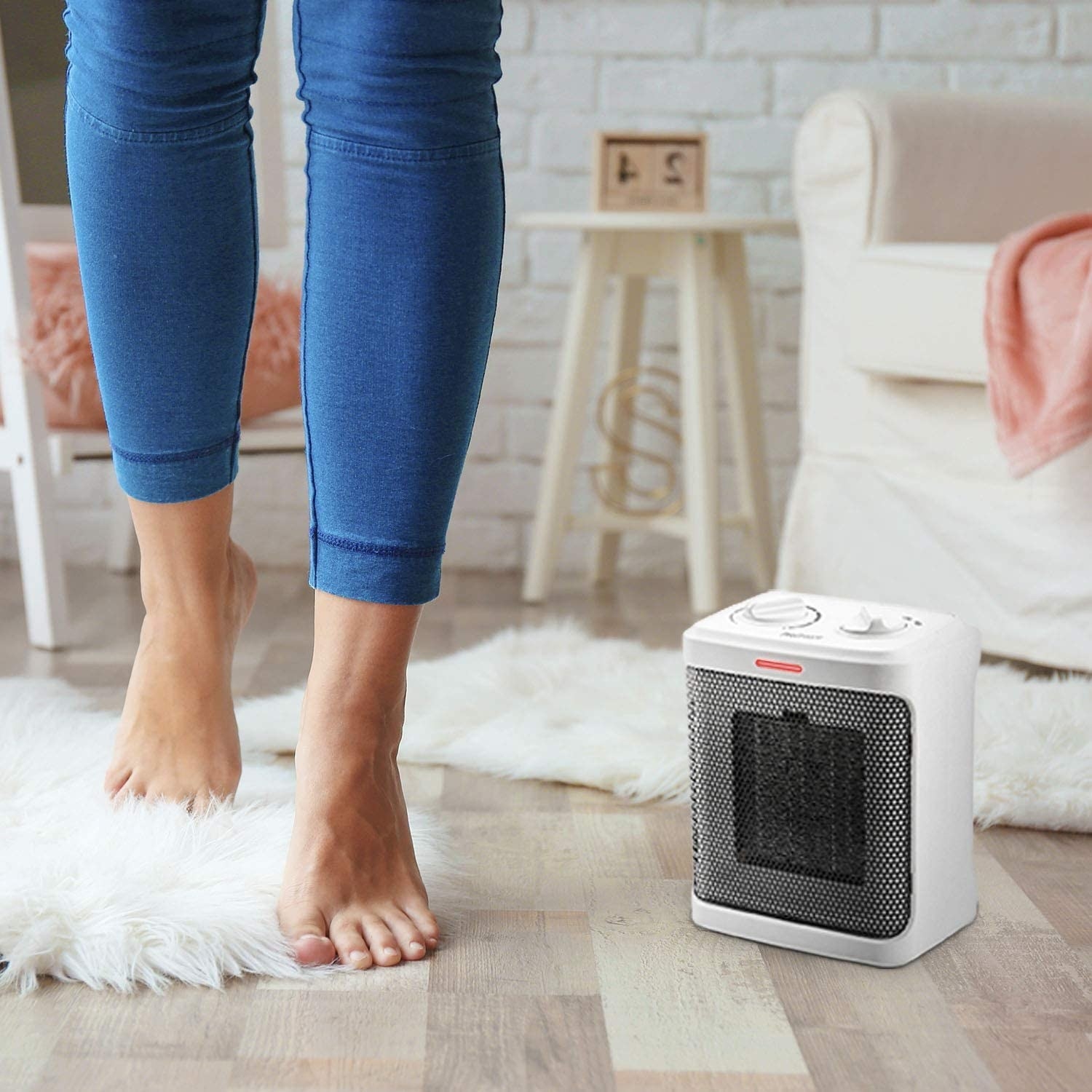 A person standing in their living room with a space heater next to their feet