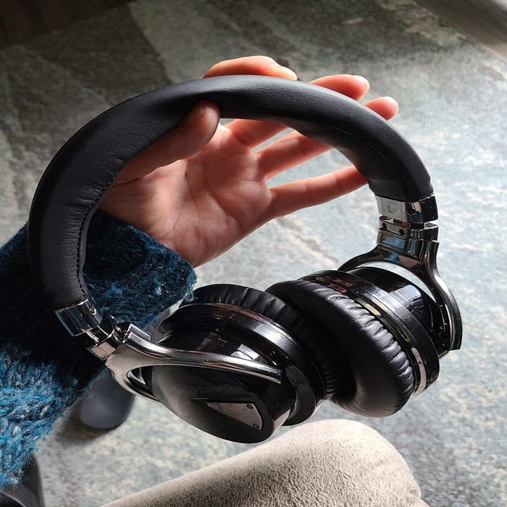 Reviewer holding headphones in hand