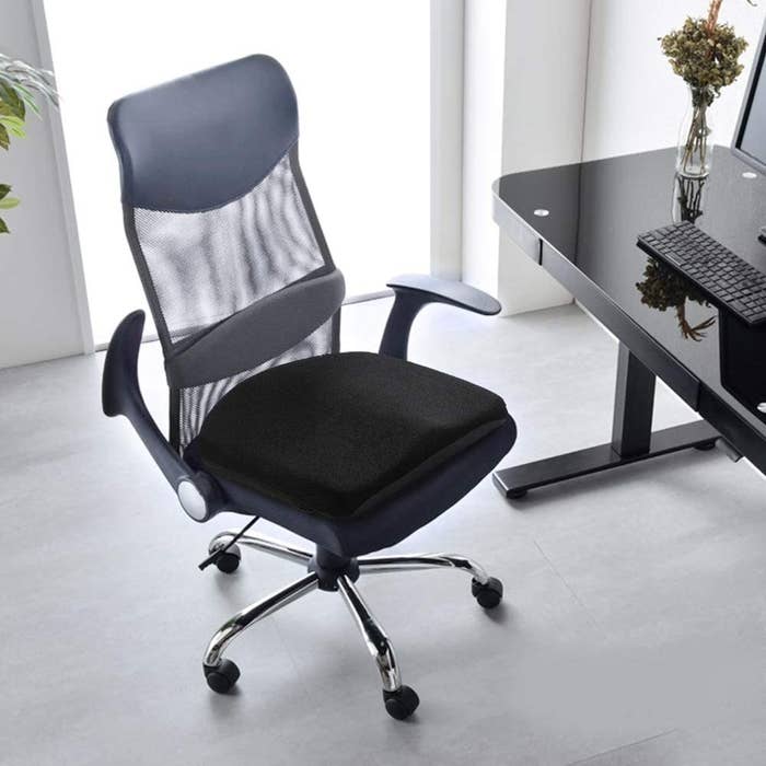 A comfy seat cushion on an swivel desk chair in front of a desk
