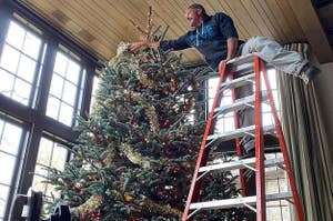 Tim McGraw standing on a ladder, decorating a massive Christmas tree