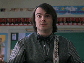 Jack Black in School of Rock holds a guitar and nods 