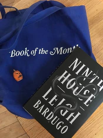 BuzzFeed Editor Bek O'Connell's blue Book of the Month tote bag with the book Ninth House by Leigh Bardugo on top of it