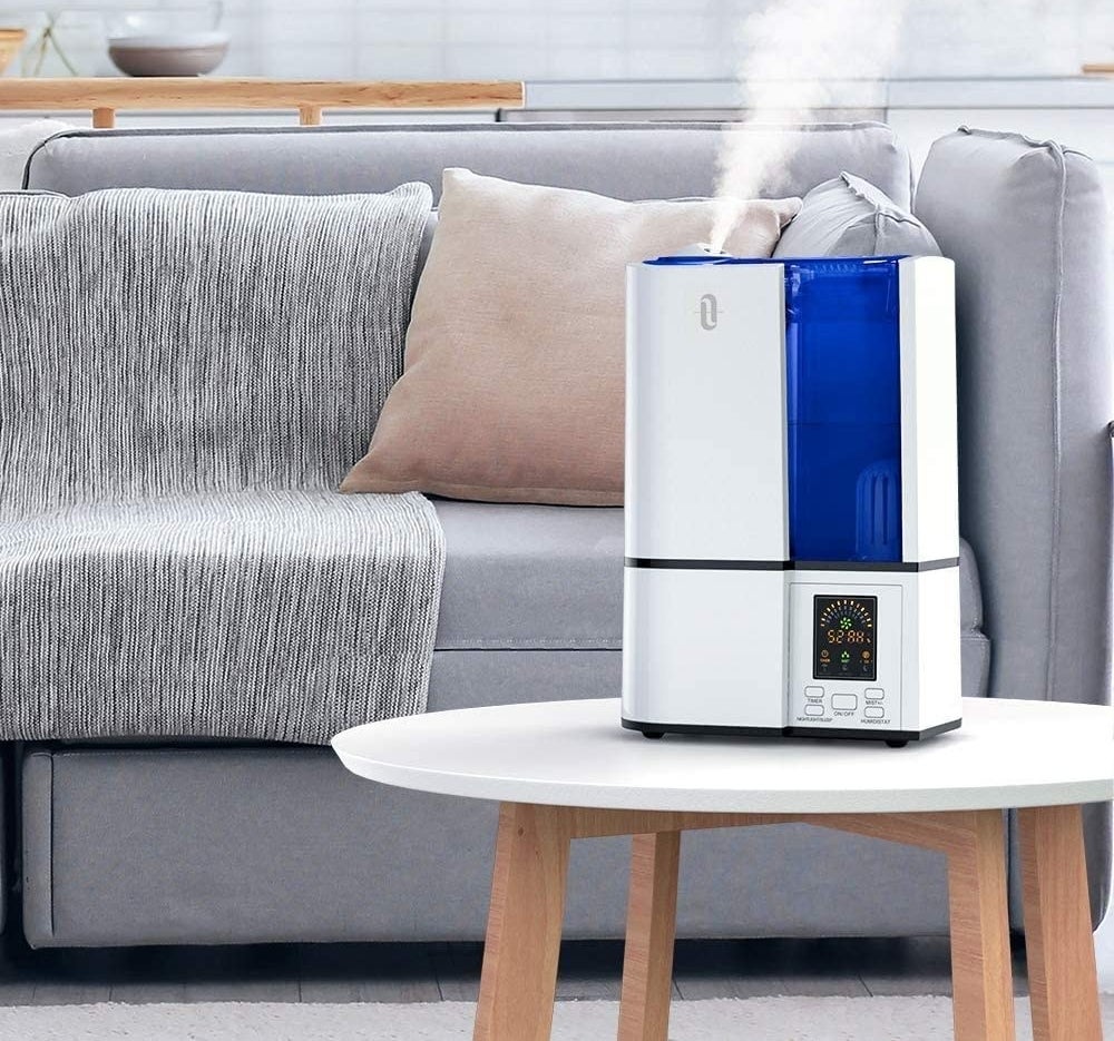 A humidifier on a low table by a couch in someone&#x27;s living room