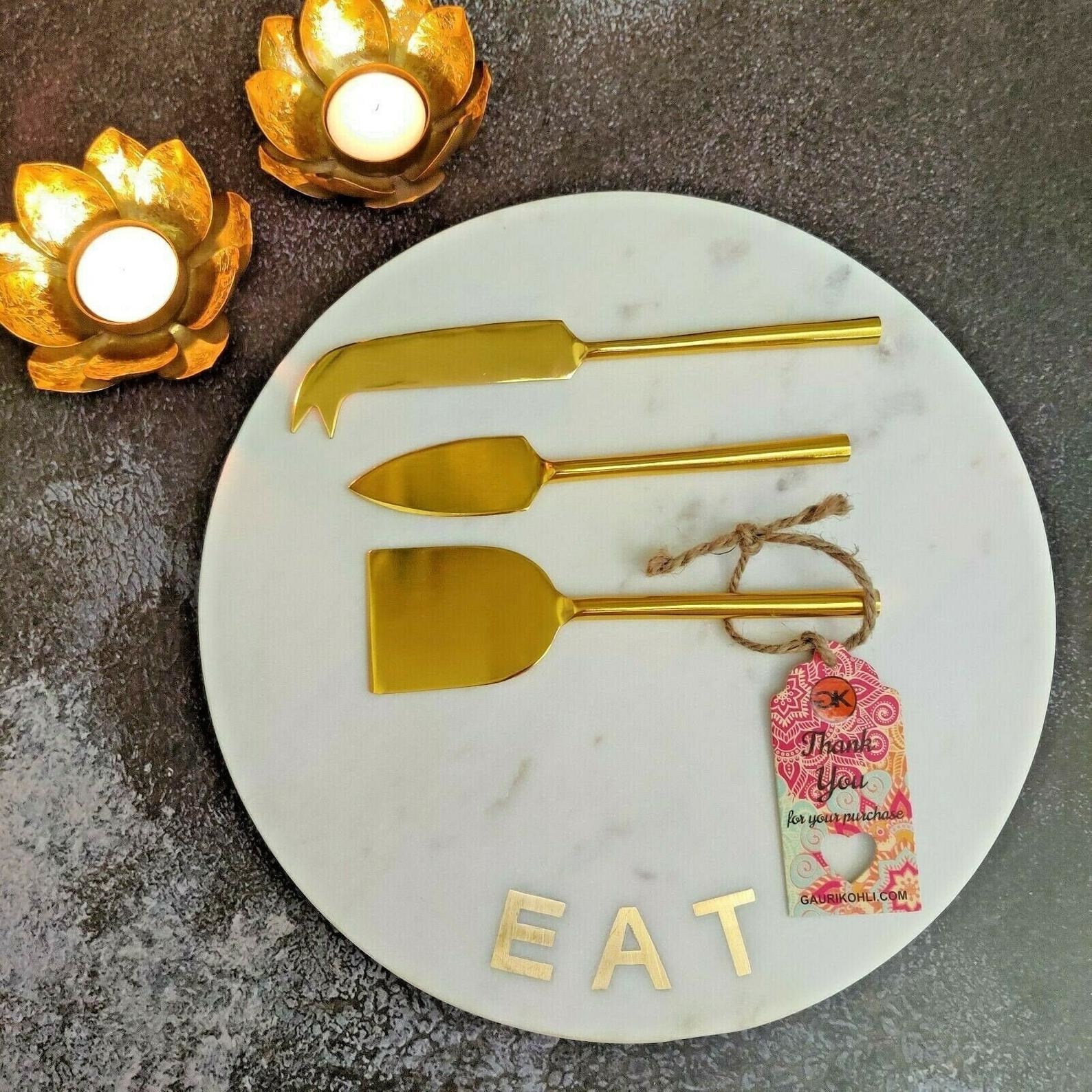 the marble plate that says eat with three gold cheese knives