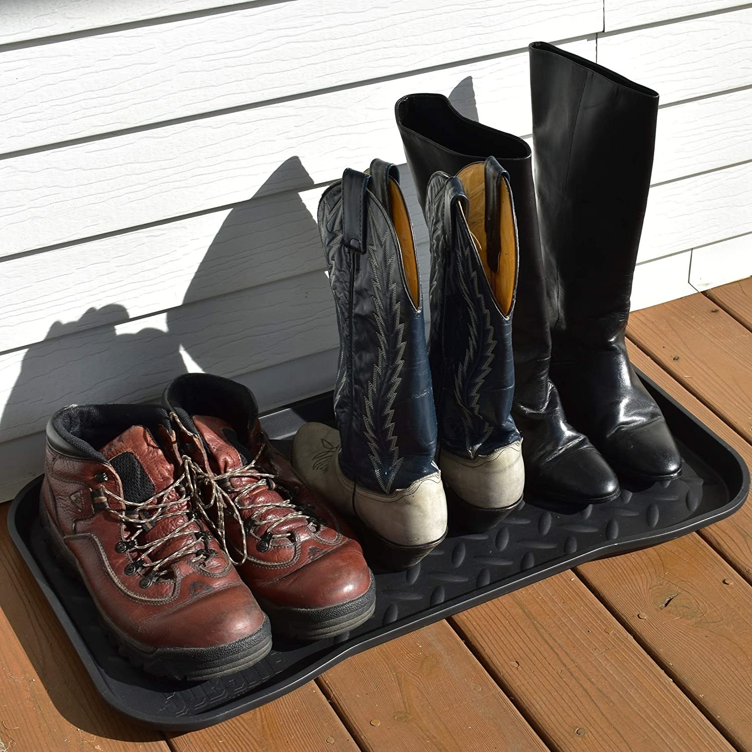 Three pairs of boots on a tray on a porch