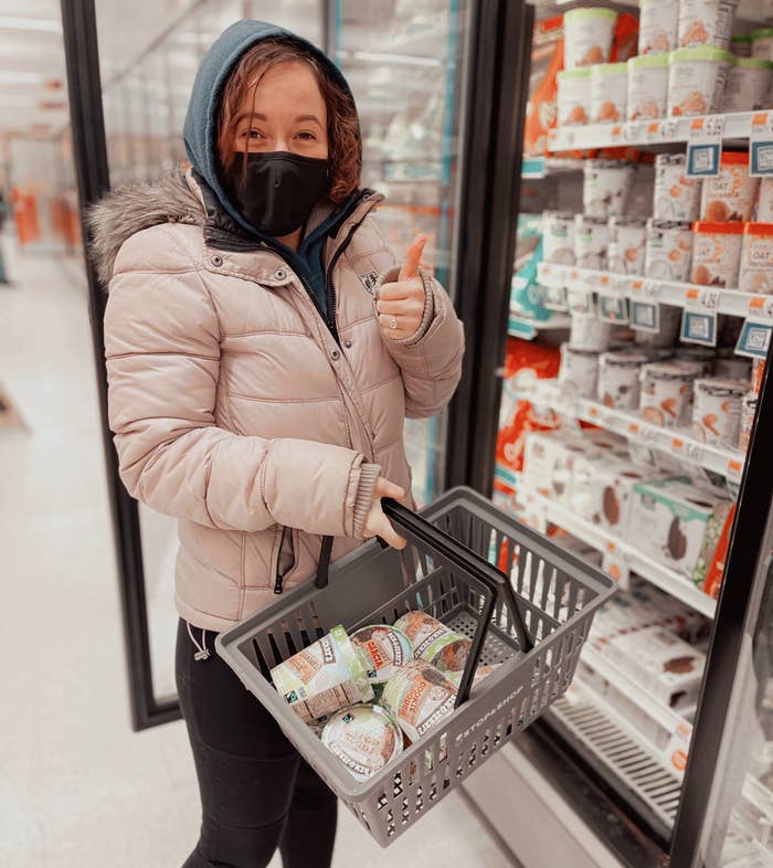 Person in a grocery store with a basket full of ice cream pints