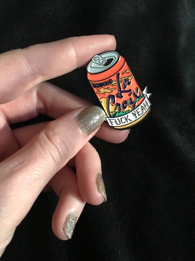 A person holding the enamel Le Croix pin 