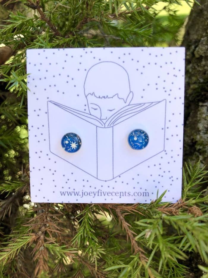 a pair of blue and white celestial stud earrings with pine tree branches 