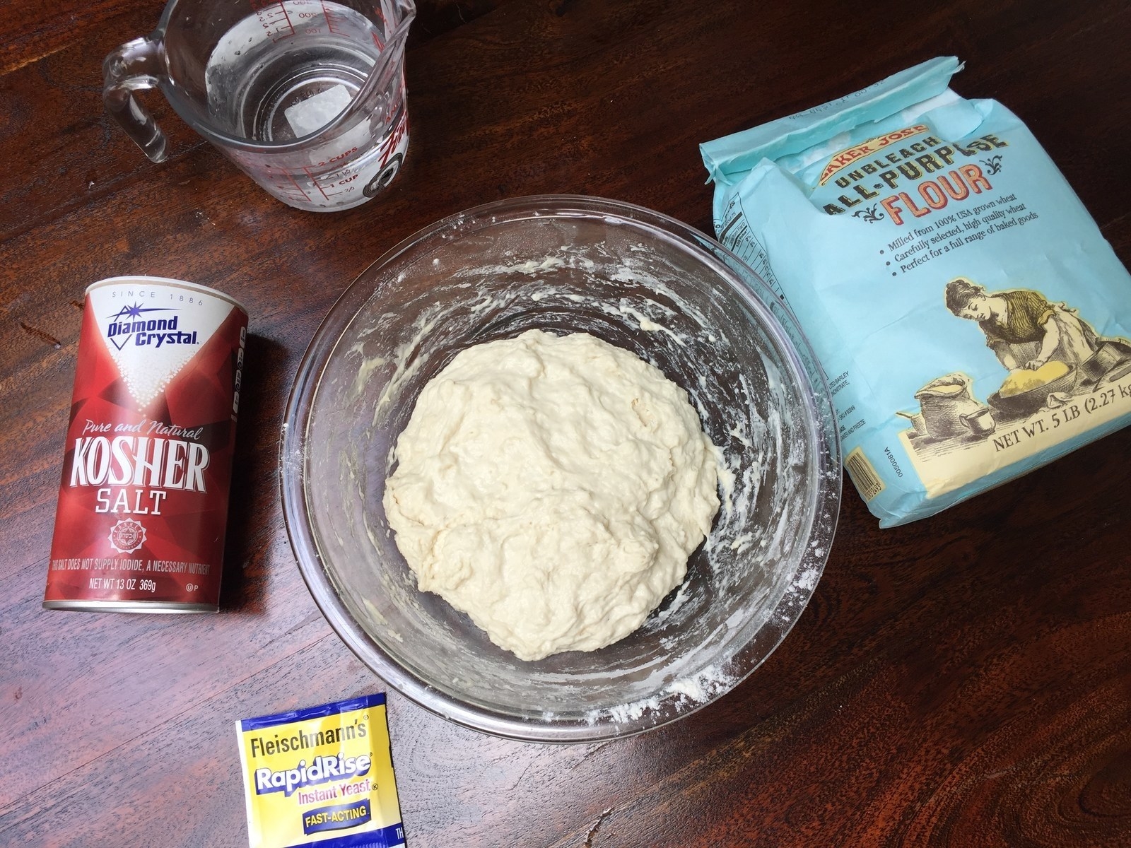 Ingredients for miracle no knead bread on a countertop: flour, salt, instant yeast, and water.