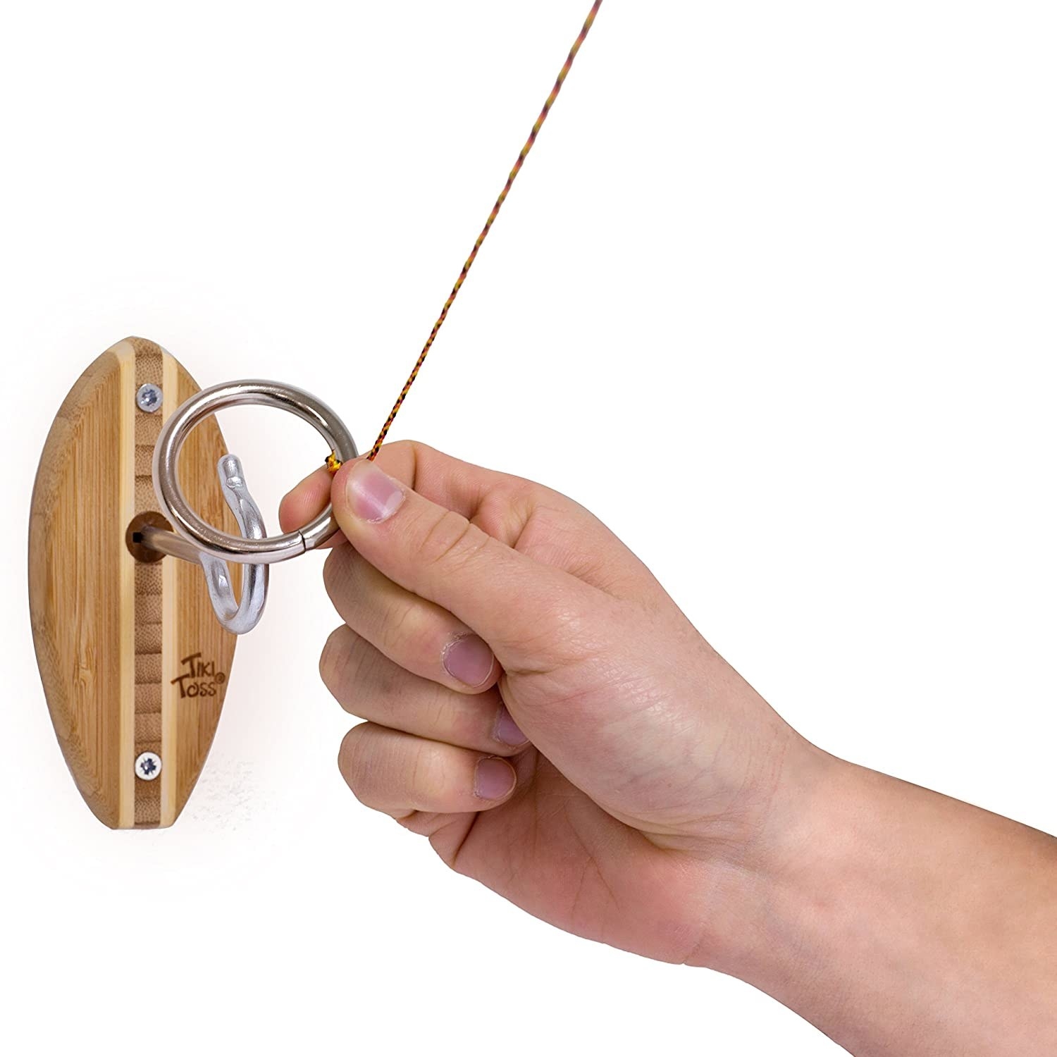A hand holding the metal ring in front of the wall-mounted wooden board