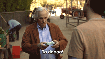 A Gif of Henry Winkler presenting a present and saying &quot;Ta daaa!&quot; 