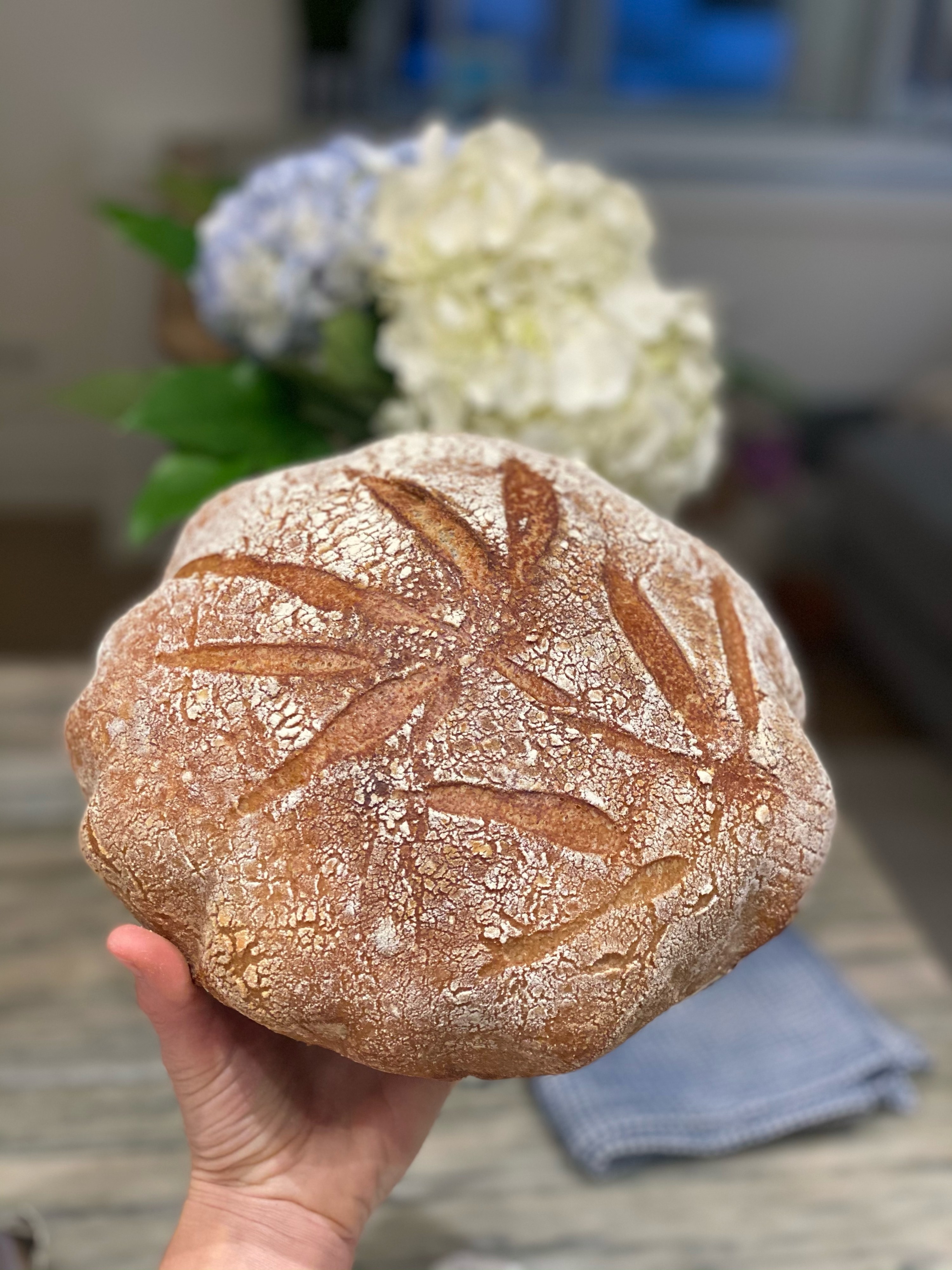 A freshly baked loaf of sourdough with artsy scoring.