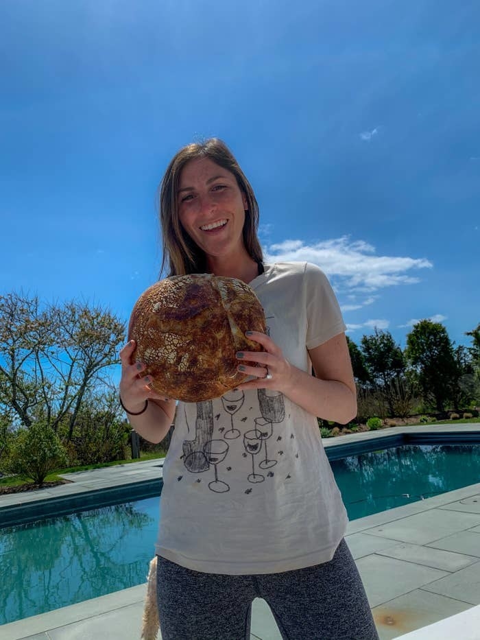 Me holding a loaf of sourdough bread that I baked.