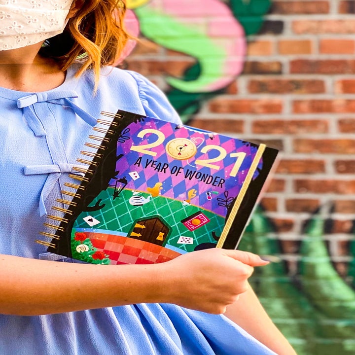 a model holding the planner with an alice in wonderland theme 