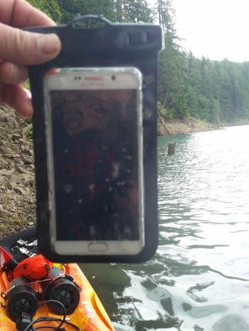 Reviewer holding a phone in the pouch above water