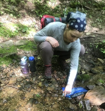 writer placing the sawer bag in a small stream