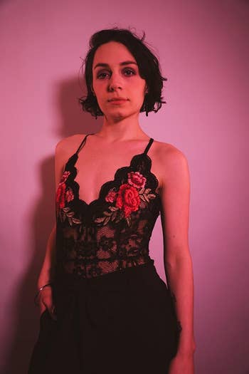 A reviewer wearing the black lace bodysuit with red embroidered flowers on the chest