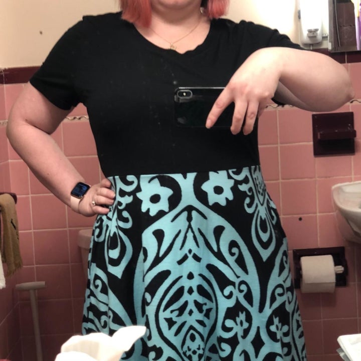 A reviewer wearing the dress with a black bodice and teal and black printed skirt