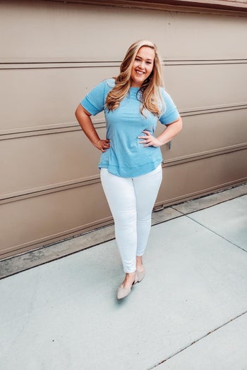 A reviewer wearing the top in light blue with white jeans