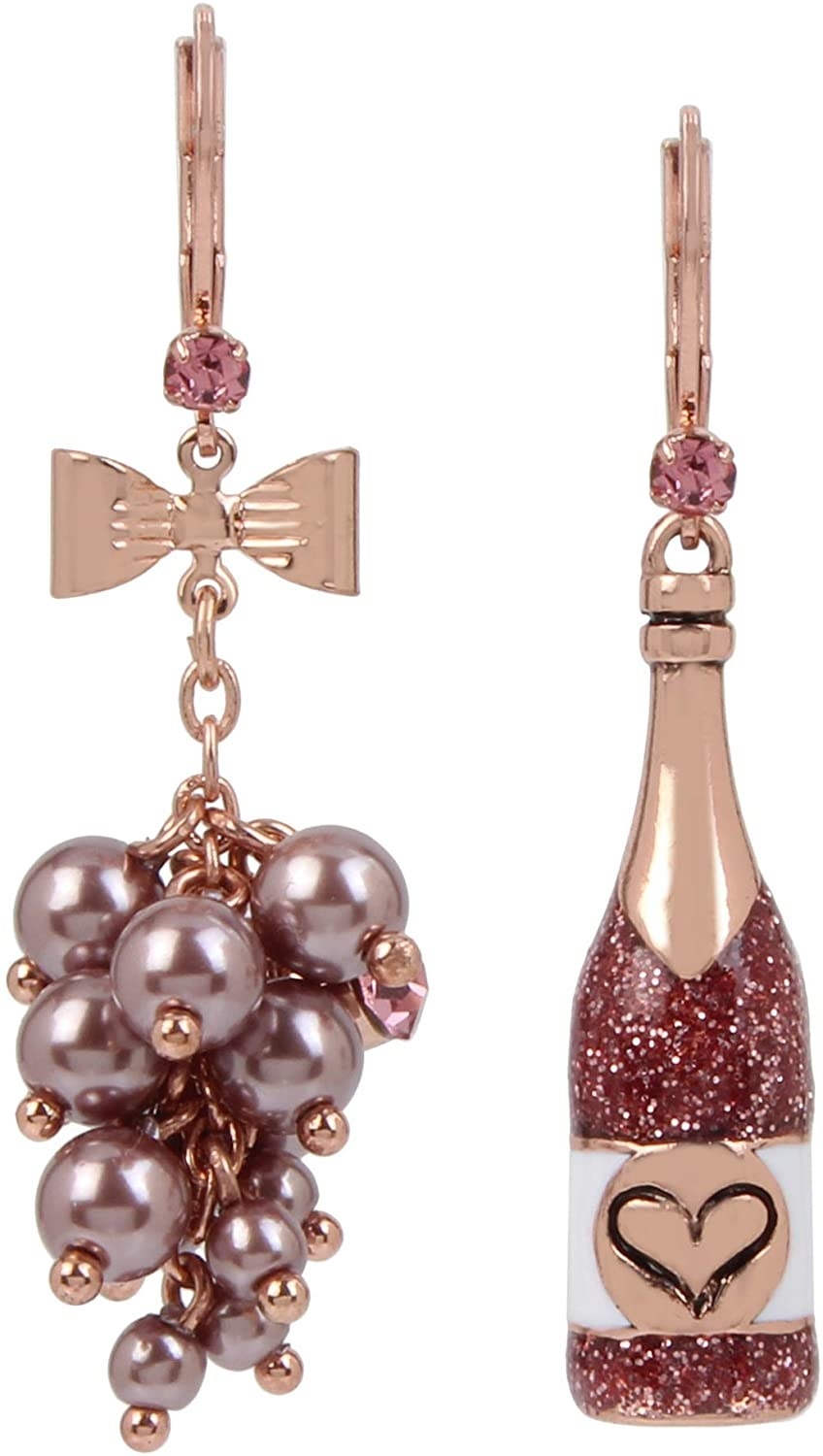The rose gold and pink rhinestone drop earrings, one of which has rose colored baubles that look like bubbles, and one that&#x27;s shaped like a glittery rosé bottle