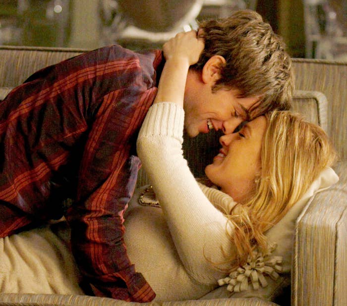 Nate and Serena on the couch on top of one another and smiling
