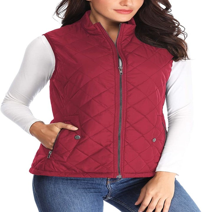 A model wearing the zip-up vest in red with a hand in one of the pockets