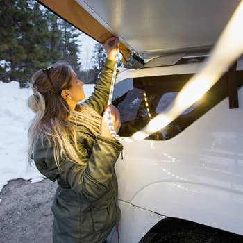 Woman attaching luminoodle to the covering above her car