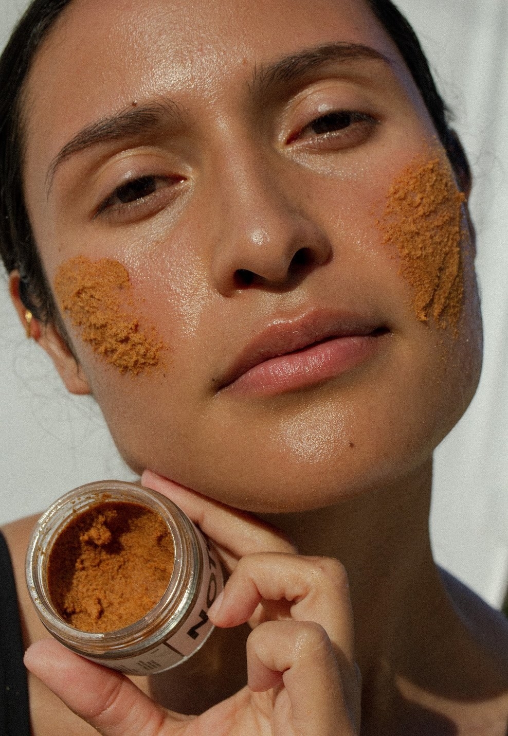 Model applies Noto Botanics&#x27; Resurface Scrub on their face