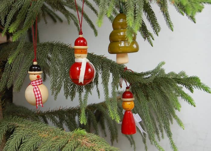 Four glossed wood ornaments shaped like a snowman, a Christmas tree and men in winter clothes.