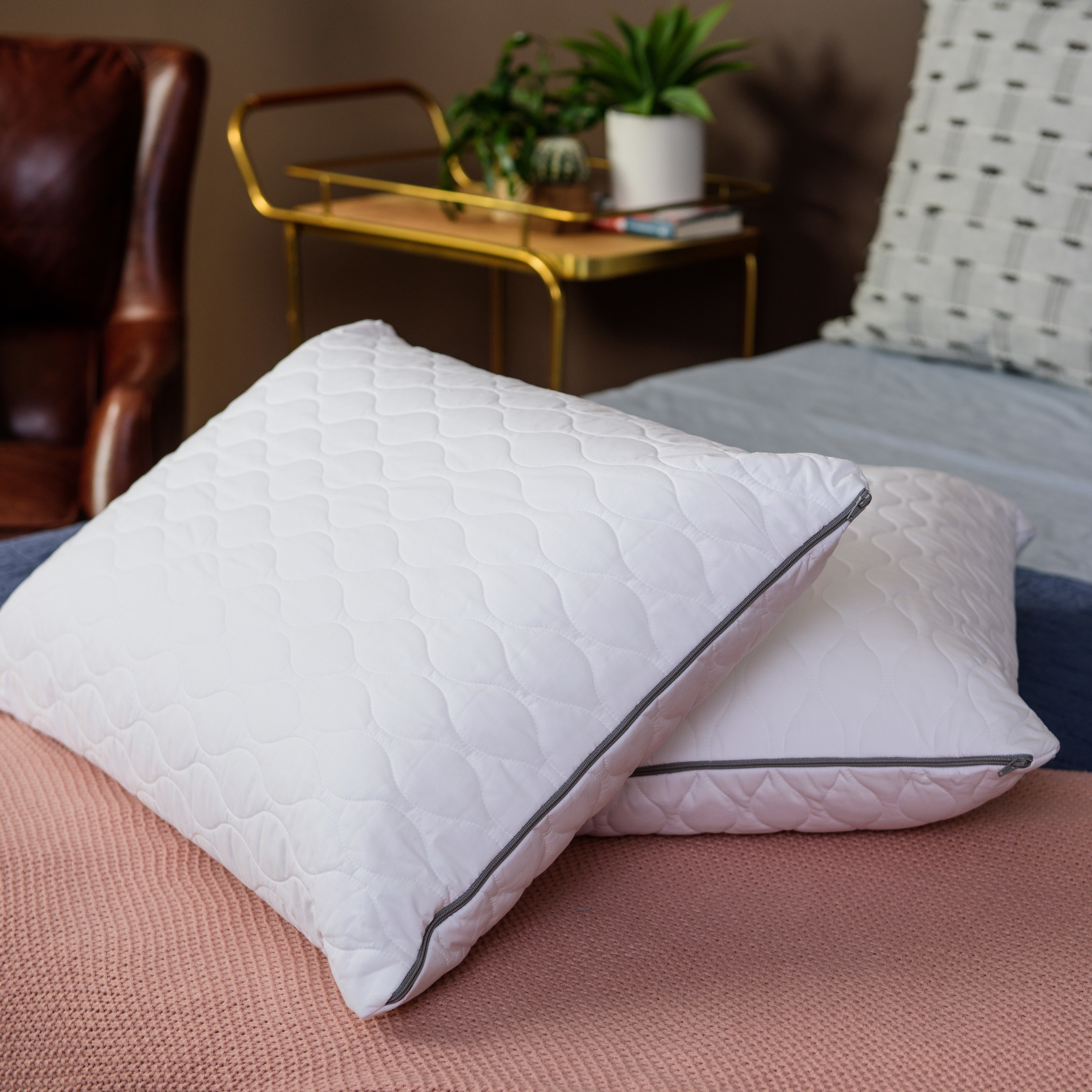 two white pillows with quilter covers on a bed