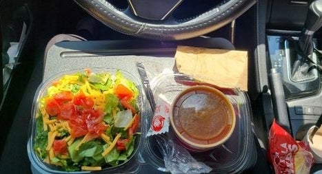 Reviewer eating a meal in their car with the lap desk 