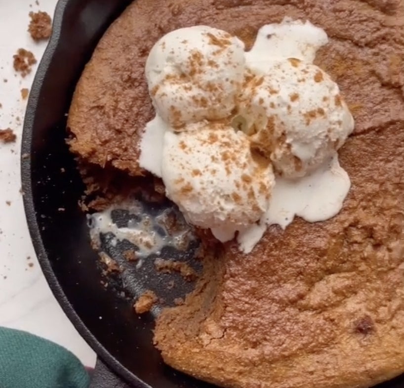 A cast iron pan filled with gingerbread and vanilla ice cream