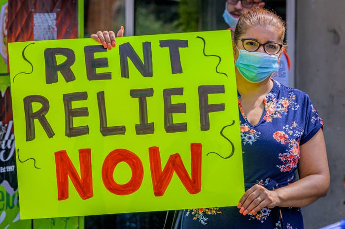 A woman with a sign that says &quot;Rent relief now&quot;