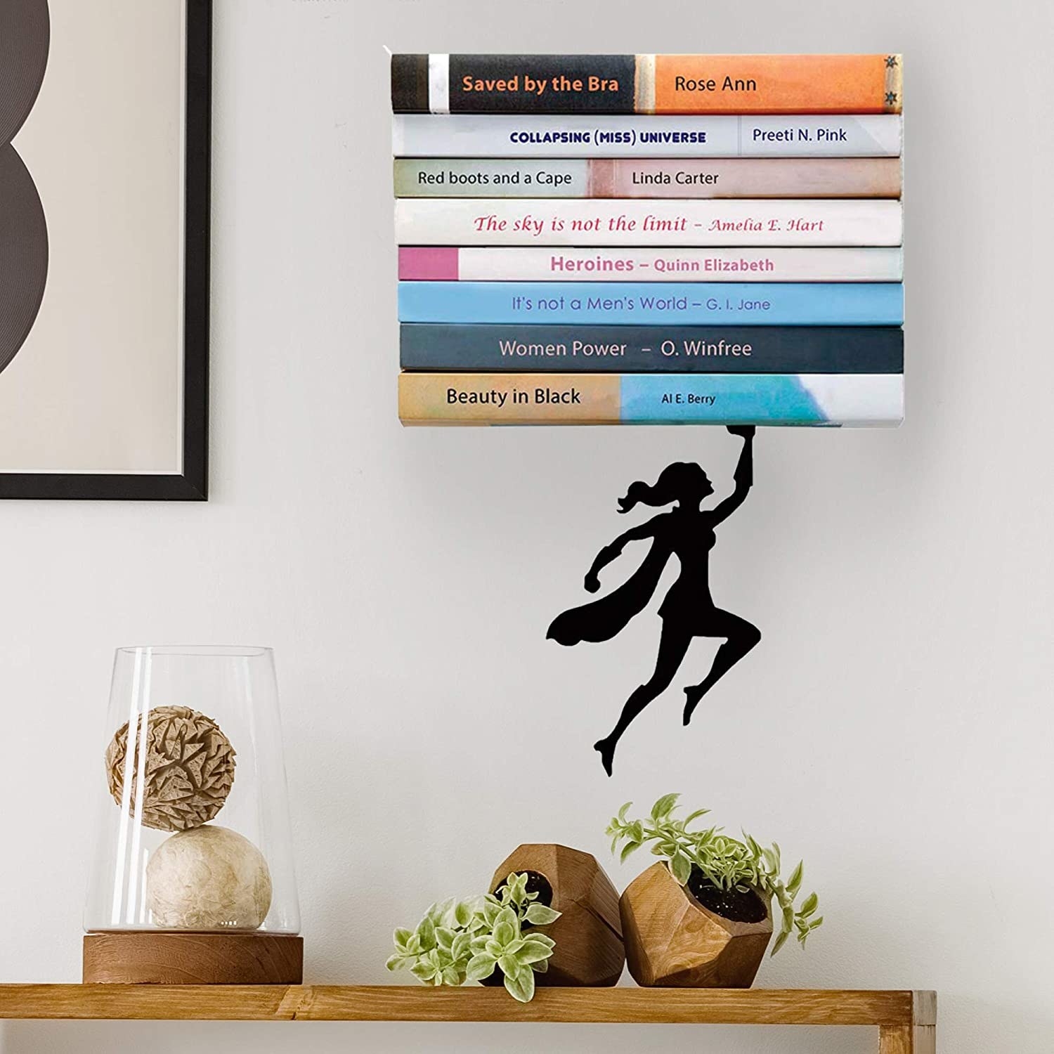 A superhero holding up a pile of books above a desk with decor and plants on it
