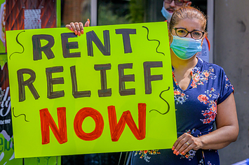 A woman with a sign that says "Rent relief now"