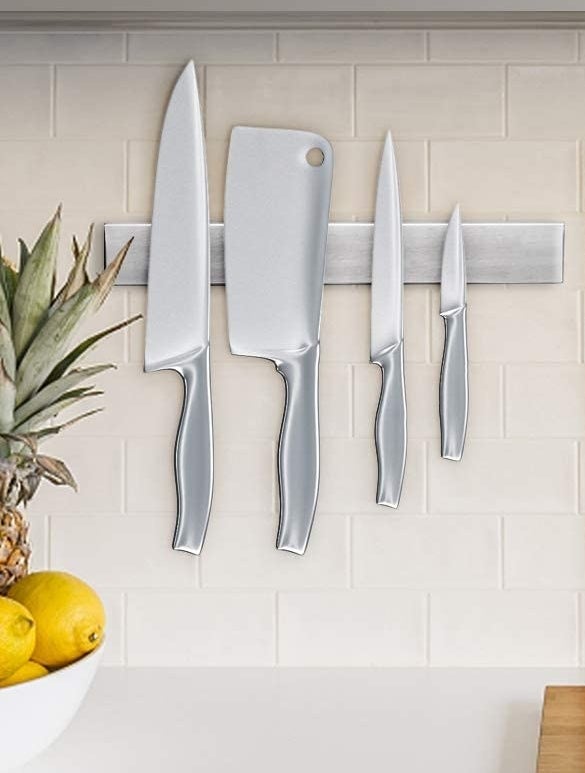 Four knives on the magnetic stip against a tiled wall