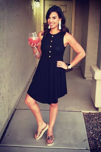 A reviewer wearing the sleeveless, above-the-knee dress with wooden buttons in black