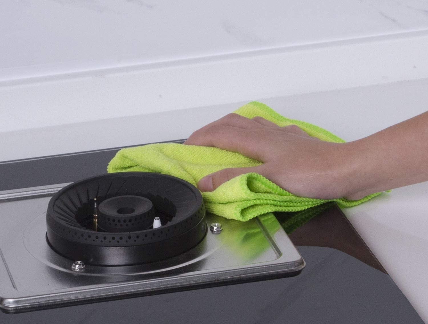 person wiping an oven unit with a microfibre towel